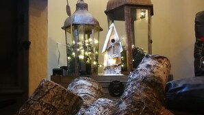 A rustic interior with a wooden log display, a lantern, and a small Christmas tree.