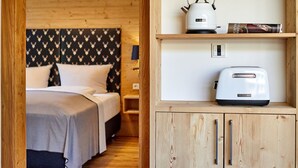 Un interior de madera con una cama, una tetera y un tostador sobre estantes.