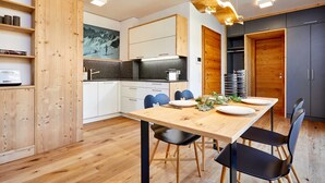 Una cocina moderna con armarios de madera, una mesa de comedor con sillas y una lámpara colgante original.