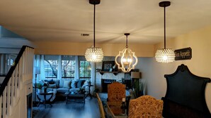 A cozy living room with a sofa, coffee table, and decorative lamps. A staircase leads to another level, and a sign reads "Bon Appetit." - 🌟LOCATION! Very Nice 2 BD 2BA Directly Across From Resort-Pool Grill Sleeps 6🏊 (Horseshoe Bay)