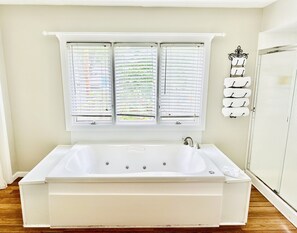 Un baño con una bañera blanca, una ventana con persianas y un perchero para toallas.