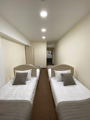 A corridor with two single beds, each with a pillow and a headboard.