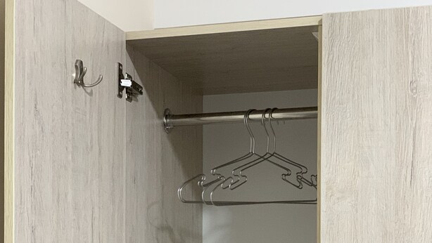 A walk-in closet with wooden doors, a metal hanger rod, and a door handle. - Hostel Paradise inn (Tashkent)