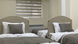 A hotel room with two beds, each with a headboard, white bedding, and a window with blinds. - Hostel Paradise inn (Tashkent)