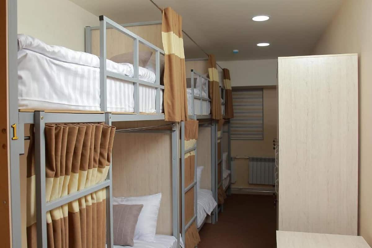 Ett studentrum med våningssängar, ett element och en dörr.