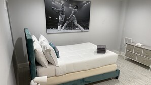 Ein modernes Schlafzimmer mit Bett, Nachttisch mit Lampe, Wandfernseher und Stauraum.