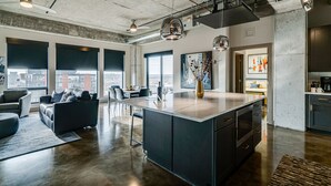 A modern kitchen with a large island, dark cabinetry, and a city view. - MINNeSTAY* Sable 901 - Penthouse | North Loop | Target Center (Minneapolis)