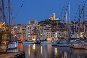 A marina with multiple boats docked, a prominent building with a dome and tower in the background, and surrounding residential buildings.