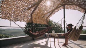 Eine Terrasse mit Blick auf die Landschaft, einer Hängematte und einem Tisch mit einem Glas Wasser.