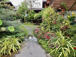 A garden pathway with lush greenery and flowering plants. - Siriwan House (Chiang Mai)