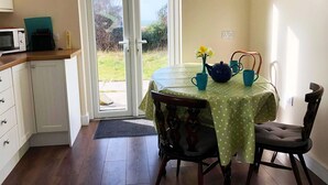 Una cocina pequeña con microondas, un reloj y un ventanal corredero que da a un jardín.