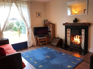 A living room with a fireplace, a television, and a bookshelf. - Steading Holidays - Ocean View (Acharacle)