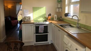 Una cocina compacta equipada con estufa, horno, lavabo y lavadora.