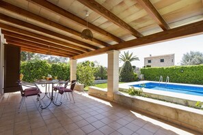 A covered patio with a pool, outdoor seating, and a view of the surrounding greenery and buildings. - Finca JACOBO, Pool, Wi-Fi, Outdoor Grill, Quiet Location, Garden, Beach: 3.5 km (Pollença)
