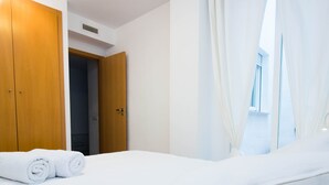 A hotel room with a bed, a wooden wardrobe, and a window with sheer curtains. - "The QUEEN" New, fancy and relaxing. Beach & WIFI (València)