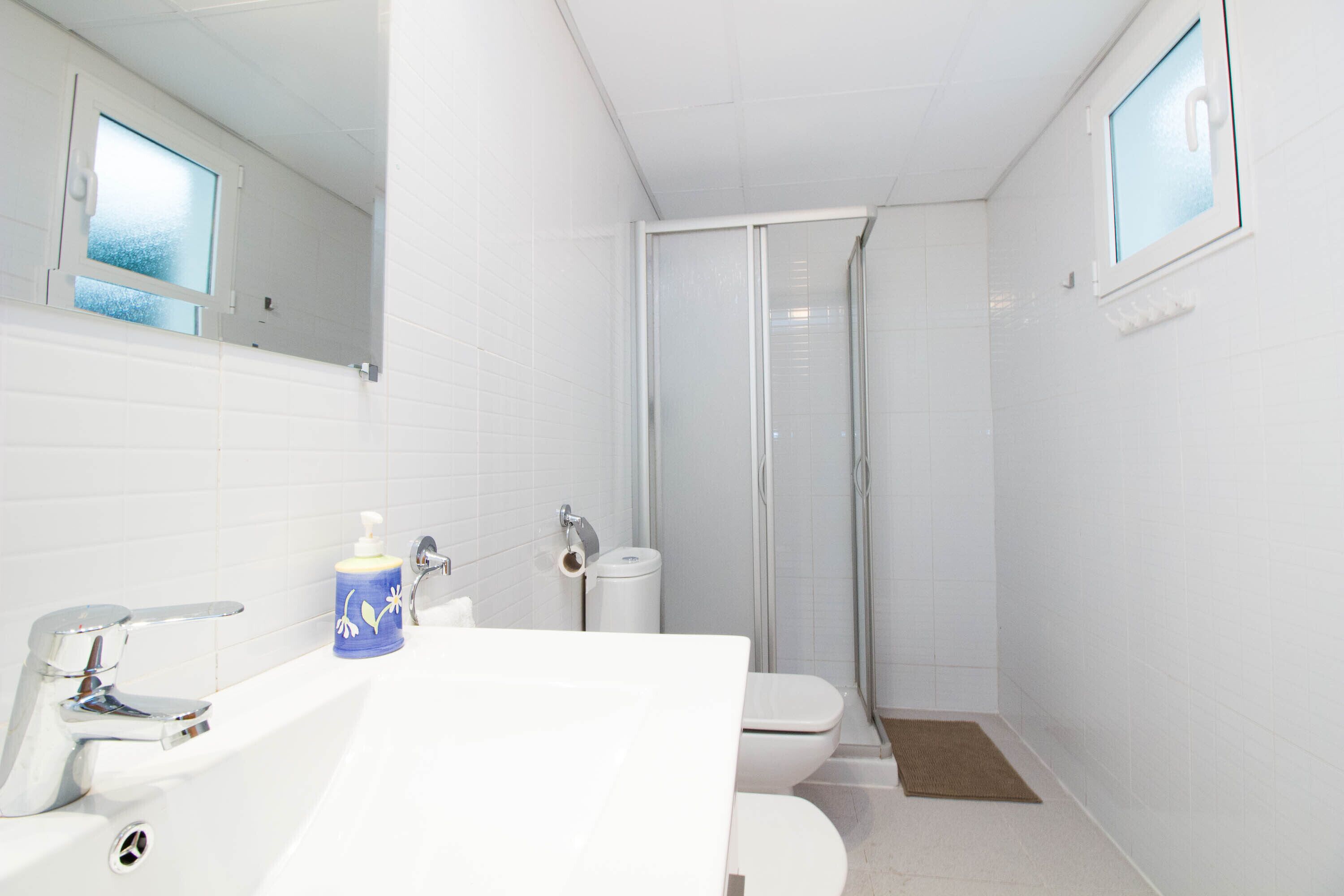 Un baño con lavamanos, inodoro y ducha blancos.