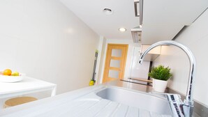 A modern kitchen with a stainless steel sink, a wooden door, and a potted plant. - "The QUEEN" New, fancy and relaxing. Beach & WIFI (València)