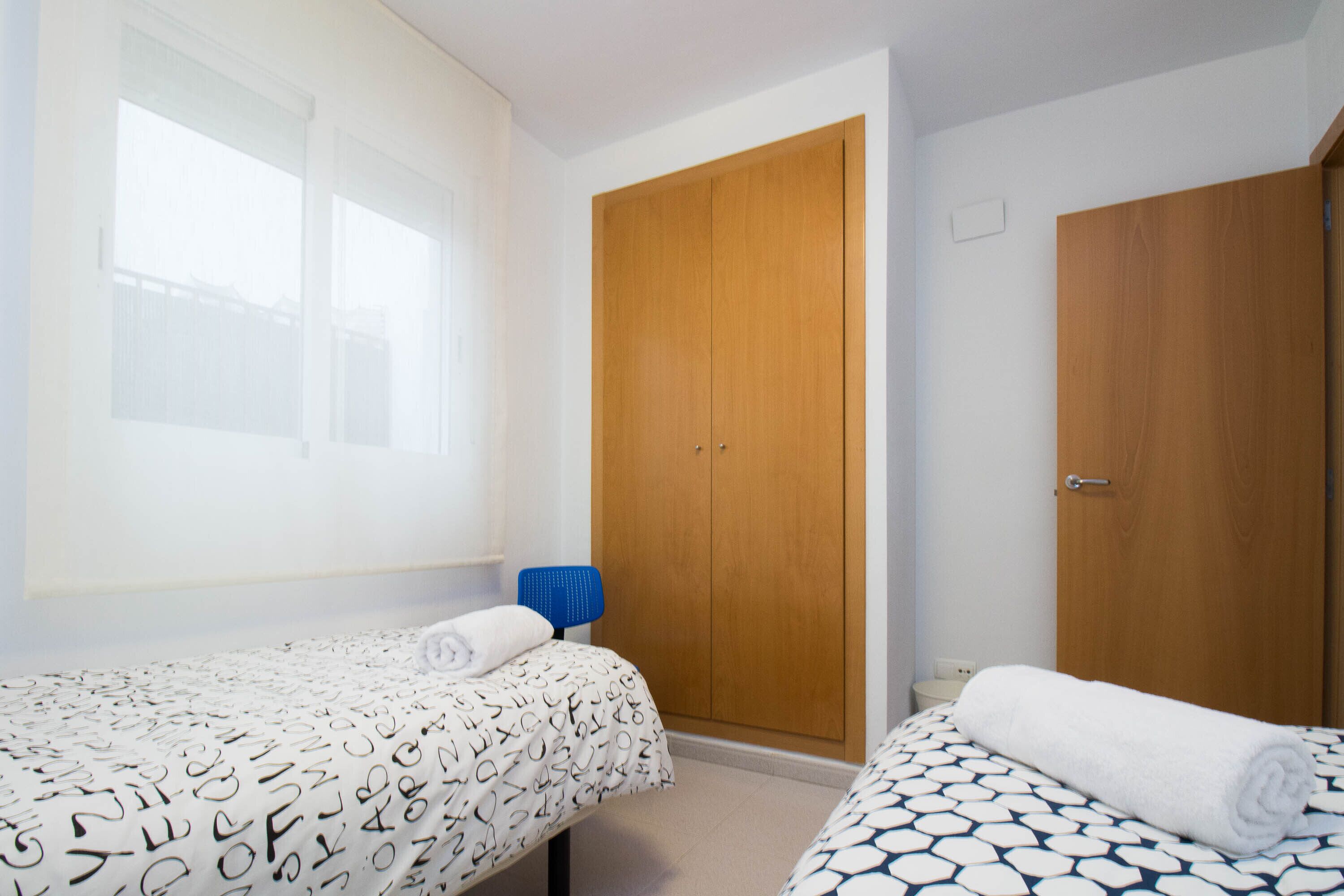 Un dormitorio con dos camas, un armario de madera y una ventana.
