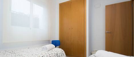 Un dormitorio con dos camas, un armario de madera y una ventana.