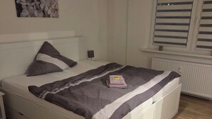 Un lit bien fait, avec une couverture à rayures, une lampe de chevet et un tableau accroché au mur.