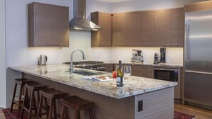 A modern kitchen with a central island, stainless steel appliances, wooden cabinets, and a red rug.