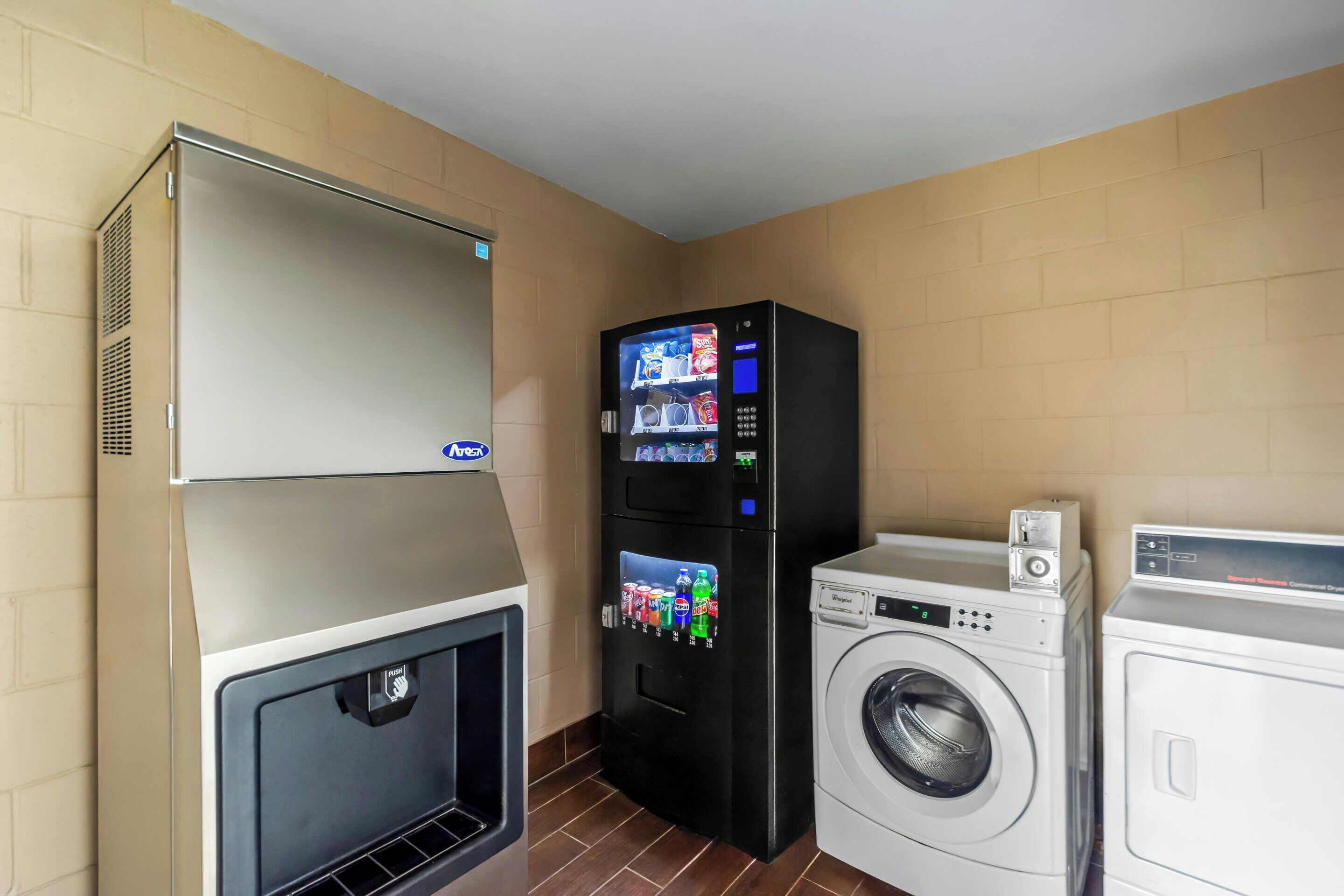 A compact hotel room with a washing machine, dryer, and a vending machine.