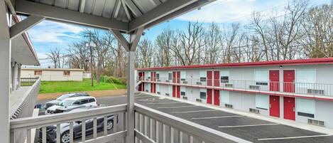 A motel with a covered parking area, a red and white building, and a view of the surrounding trees.