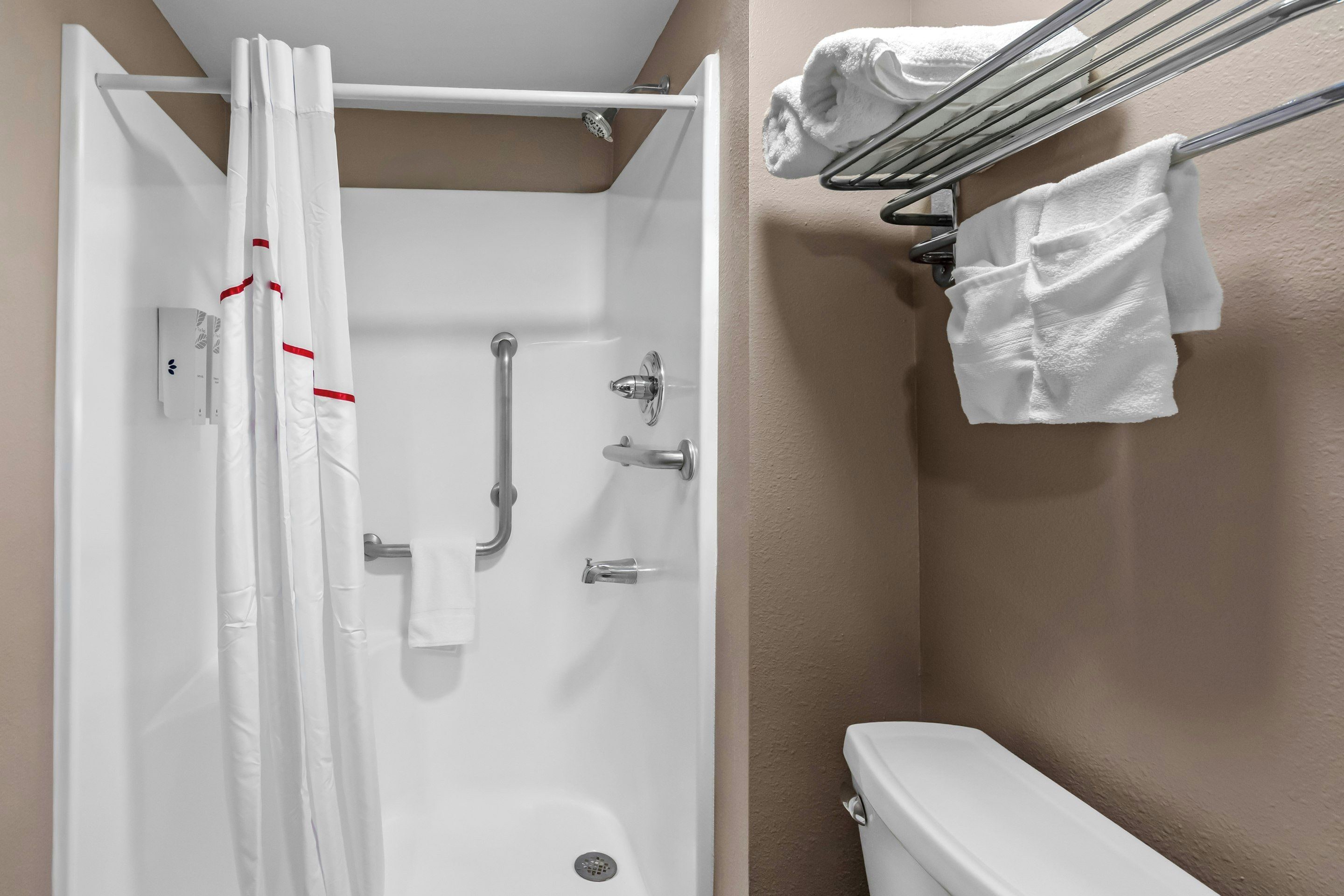 Une salle de bain équipée d’une douche, de toilettes, d’un porte-serviettes et d’un sèche-mains.