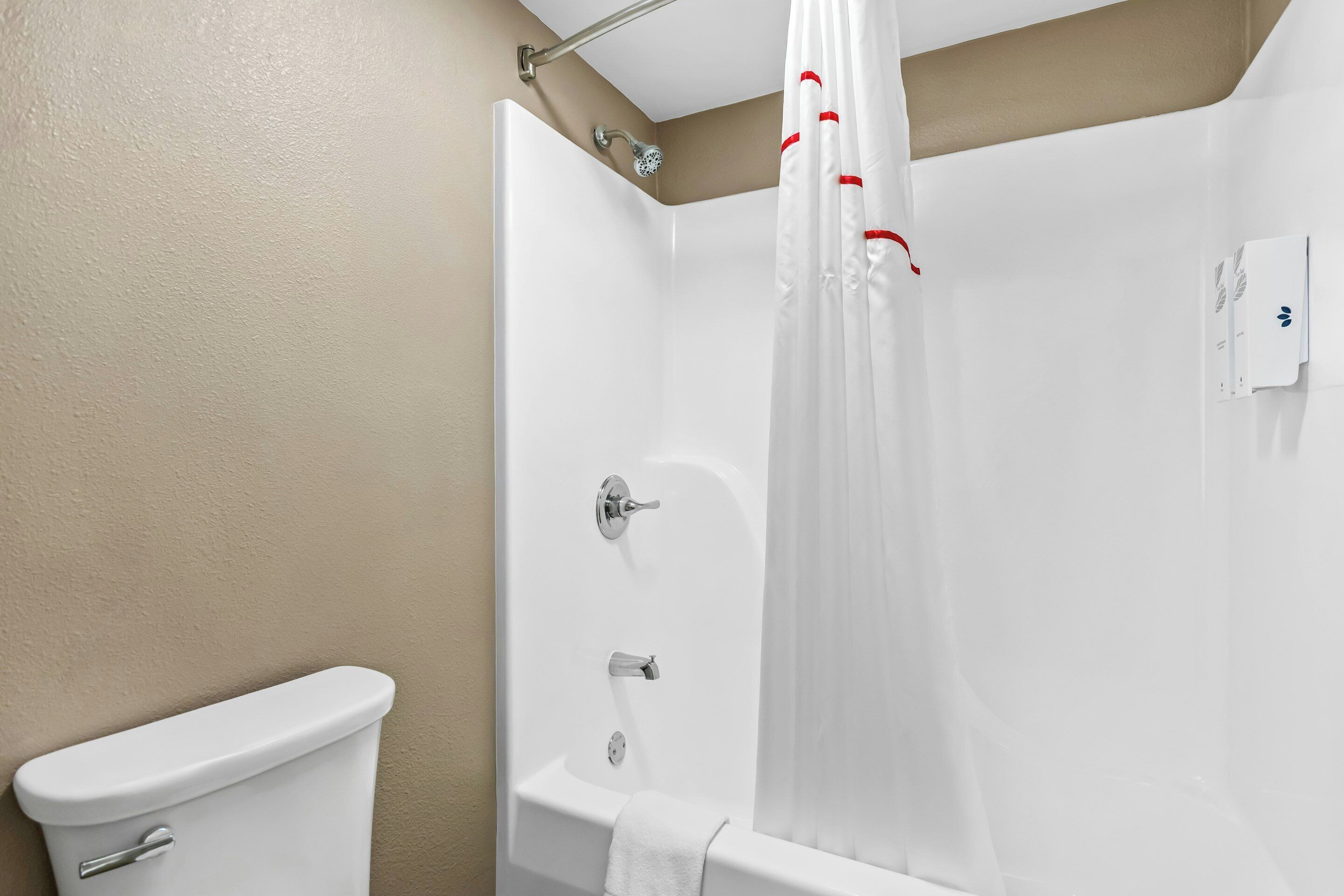 Une salle de bain équipée de toilettes, d’une baignoire et d’un rideau de douche.