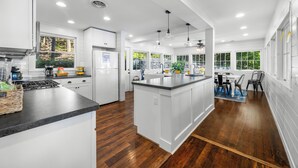 Une cuisine moderne avec des meubles blancs, un îlot central et un coin repas comprenant une table et des chaises.