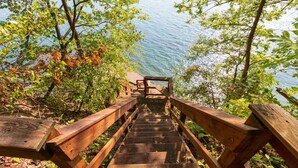 Un escalier en bois mène à un point de vue surplombant une étendue d’eau, le tout étant entouré d’arbres.