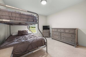 A bunk bed with a television and a dresser in a room with carpeted flooring. - Gracie's Place: Stunning Lakefront Escape on Seneca Lake! (Romulus)