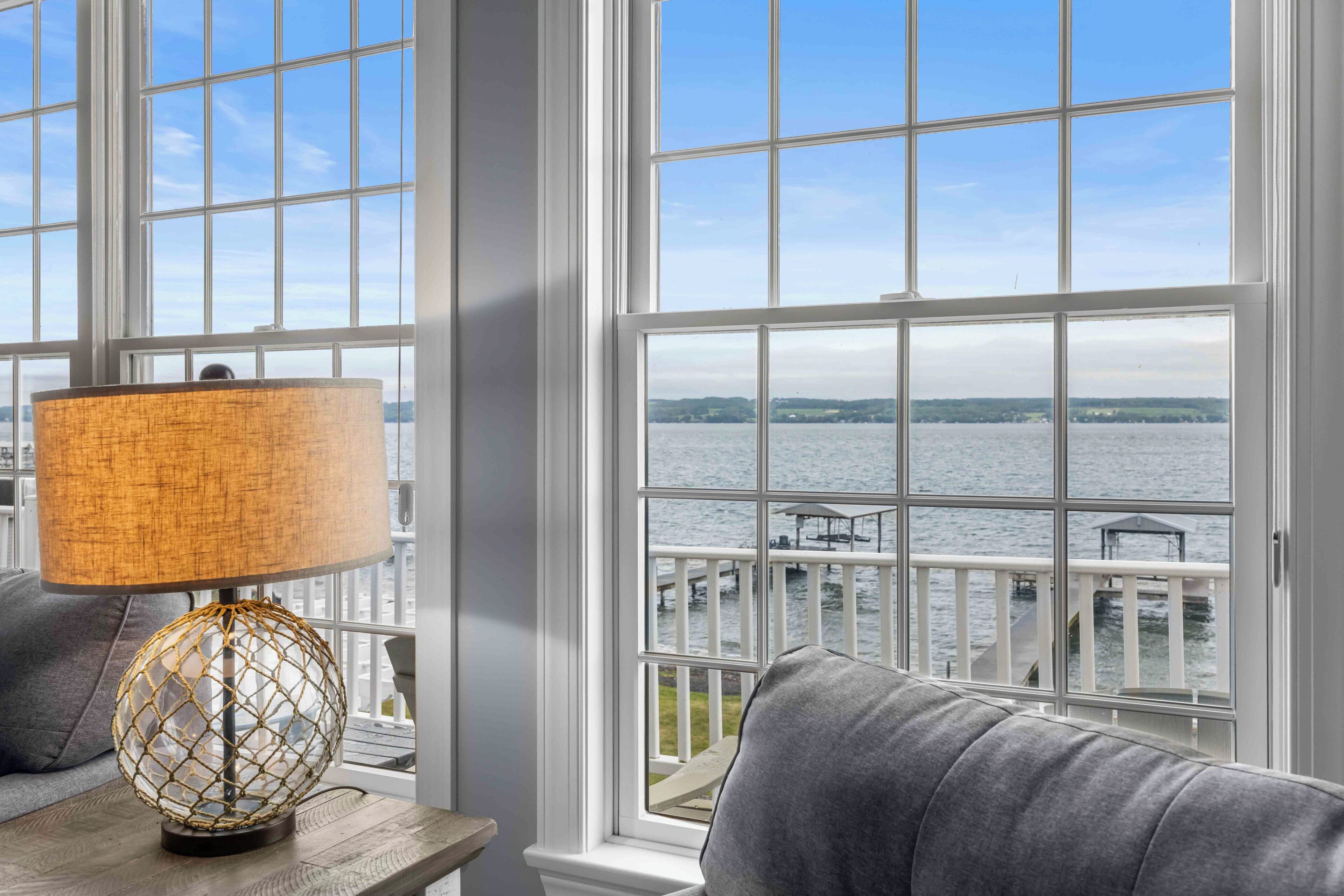 A room with a view of a body of water, a lamp, and a sofa.