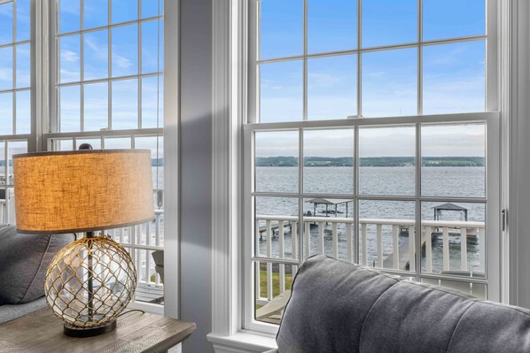 A room with a view of a body of water, a lamp, and a sofa.