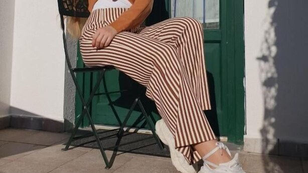 A person sitting on a chair outside a building with a green door and white walls. - Ristorante B&B Posidonia (Sapri)