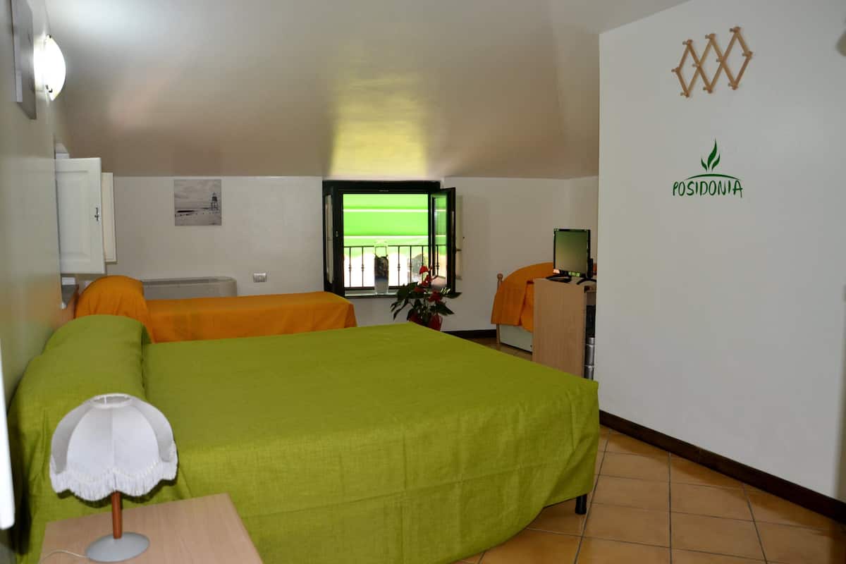 A hotel room with a bed, a desk, a chair, a lamp, a window, and a wall with a logo.