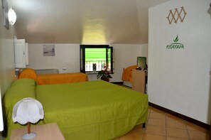 Habitación de hotel con cama, escritorio, silla, lámpara, ventana y una pared con un logotipo.