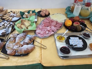Una mesa de buffet con diversos alimentos, como pasteles, carnes, frutas y salsas.