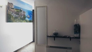 A bathroom with a white door, a shelf with a vase and a bottle, and a painting on the wall. - Ristorante B&B Posidonia (Sapri)