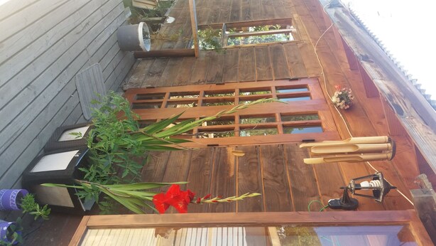 A wooden deck with a glass enclosure, potted plants, and a hanging lantern. - House with terrace near the lake, national parks and caburgua eyes (Pucon)