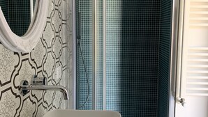 A bathroom with a white sink, a mirror, and a shower with a glass door. - Palazzo Samà (Catanzaro)