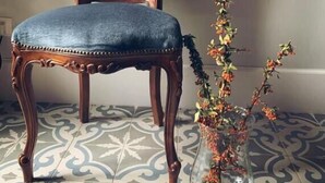 A chair with a tufted backrest and a floral vase on a patterned floor. - Palazzo Samà (Catanzaro)