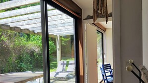 Una habitación con un gran ventanal corredero que da a una terraza exterior con una mesa y sillas de madera.