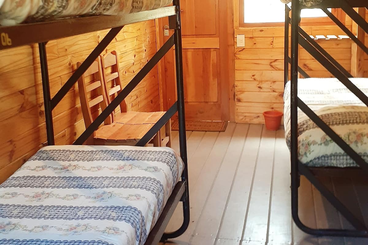 Eine Holzhütte mit zwei Etagenbetten, Holzwänden, einem Fenster und einer Tür.