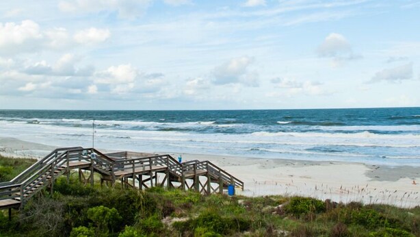 A wooden boardwalk leading to a beach with waves crashing onto the shore.