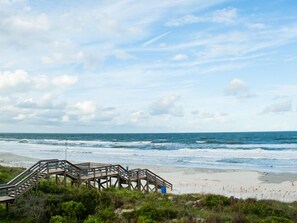 A wooden boardwalk leading to a beach with waves crashing onto the shore.