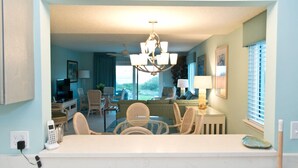 A modern kitchen with a dining area, a living room with a view, and a chandelier.