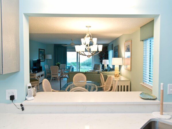 A modern kitchen with a dining area, a living room with a view, and a chandelier.