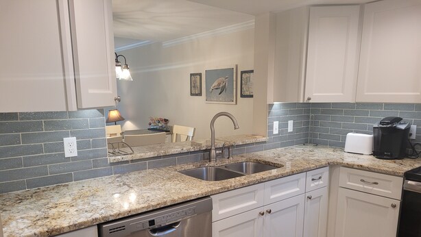 A modern kitchen with granite countertops, stainless steel appliances, and white cabinetry. - Oceanview from balcony 3 Bedroom 2 Bath ground floor Unit - 110 (ST. AUGUSTINE)