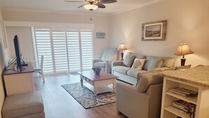 A living room with a sofa, armchairs, a coffee table, and a bookshelf. - Oceanview from balcony 3 Bedroom 2 Bath ground floor Unit - 110 (ST. AUGUSTINE)